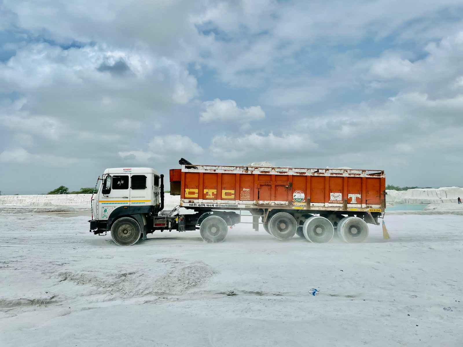 a dump truck driving on a sandy beach